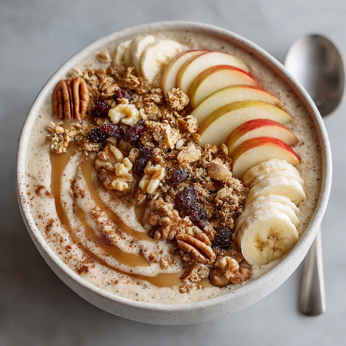 A close-up of a creamy Apple Pie Smoothie Bowl: sliced apples and chopped walnuts.