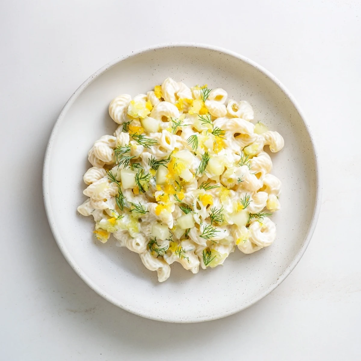 A close-up shot of a creamy bowl of Pickle Mac and Cheese, speckled with bright green pickles.