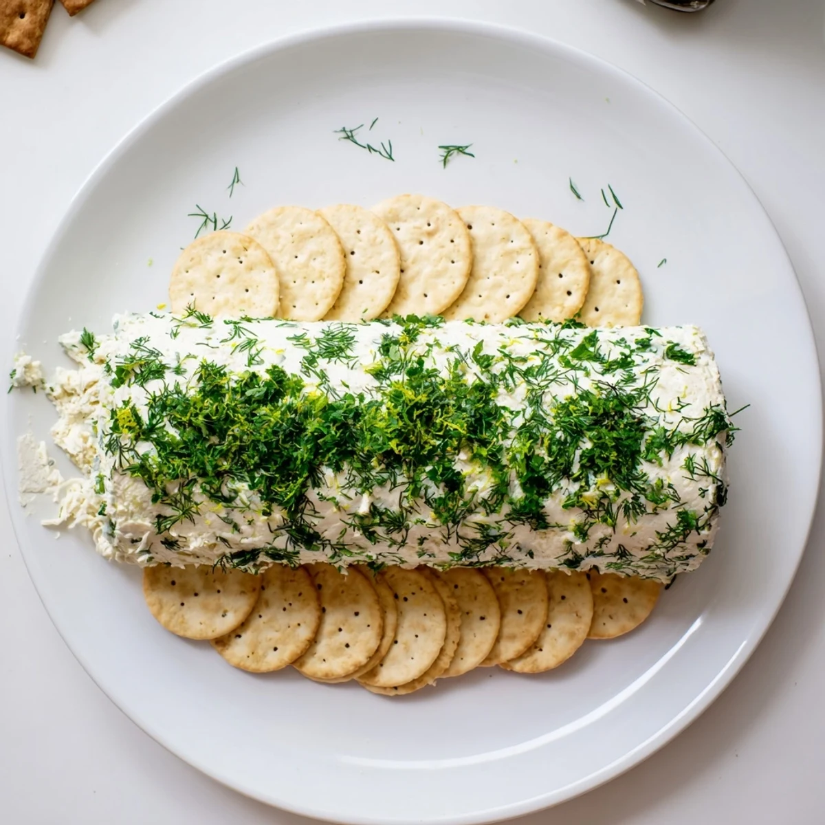 Tangy herb-coated cheese log, a beautiful appetizer on a platter with crackers for dipping.