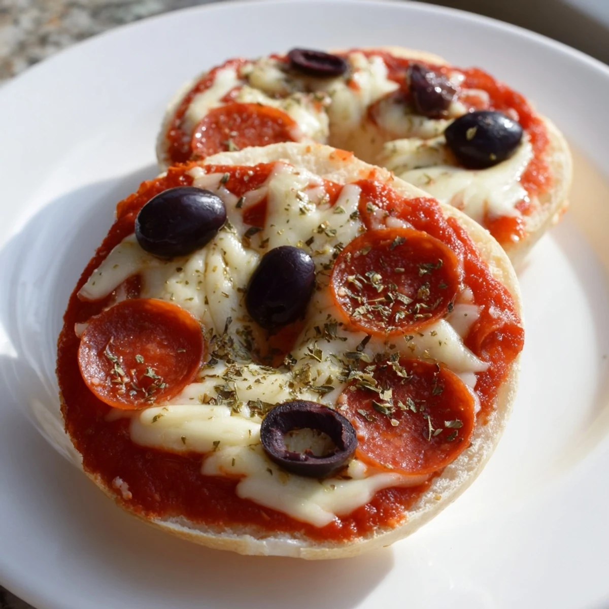 Golden, bubbly mini bagel pizzas with melted cheese and crispy pepperoni, perfect snack.