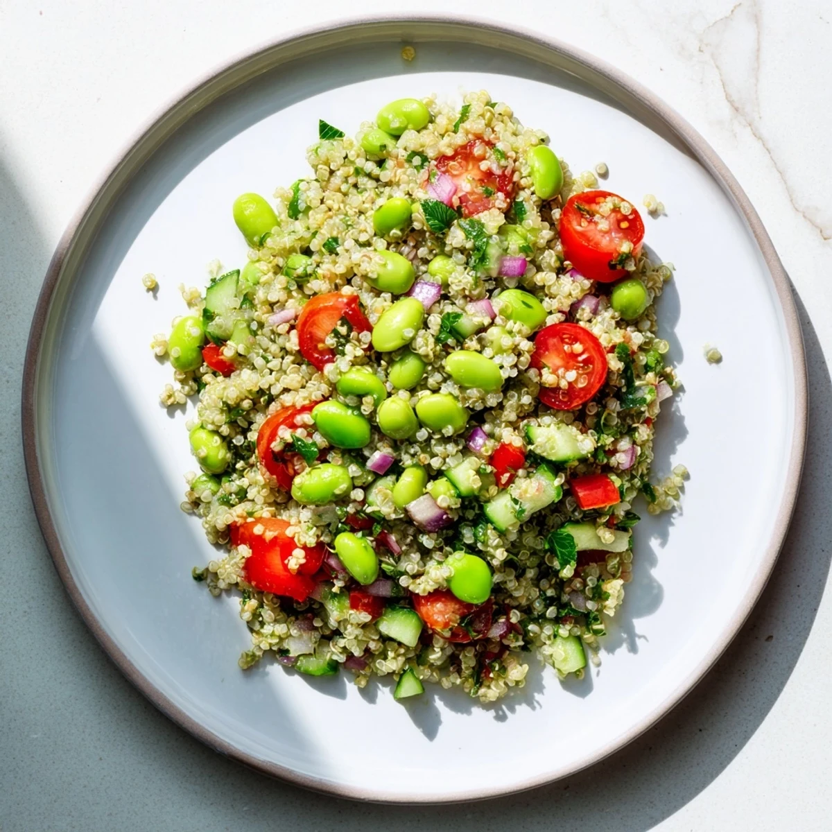 A vibrant bowl of Edamame and Quinoa Salad, tossed with bright red cherry tomatoes and fresh herbs for a protein-packed lunch.