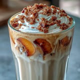Iced chai latte crowned with fluffy peach cobbler cold foam and spice.