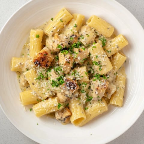 Golden chicken and rigatoni swimming in a rich, creamy garlic Parmesan sauce ready to serve.