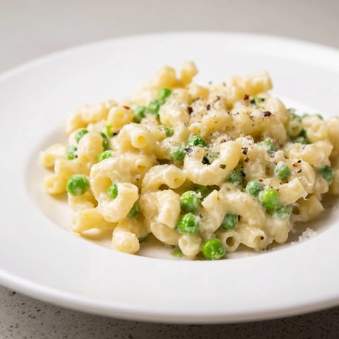 Creamy macaroni & peas, a comforting bowl of pasta with parmesan cheese, ready to eat.