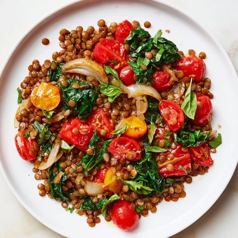 Steaming Lentil-Tomato Skillet, showcasing vibrant red tomatoes with fresh herbs, a delicious vegetarian supper.