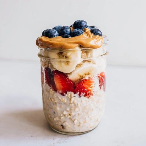 Overnight Oats jars with colorful layers of fruit and creamy peanut butter, perfect for a grab-and-go breakfast.