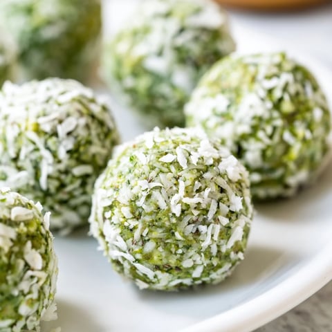 Creamy Coconut Matcha Snowball fat bombs covered in coconut flakes, a keto-friendly dessert.