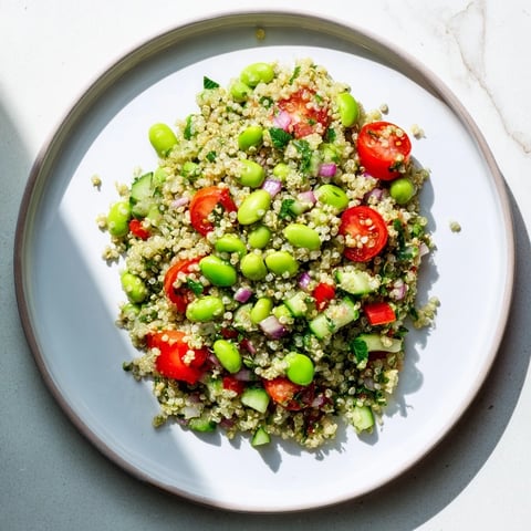 A vibrant bowl of Edamame and Quinoa Salad, tossed with bright red cherry tomatoes and fresh herbs for a protein-packed lunch.