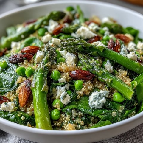 A close-up of a vibrant Spring Green Bowl, highlighting bright peas, tender asparagus, and fresh spinach on fluffy quinoa.