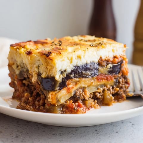 Layers of Moussaka with Beef & Eggplant, golden béchamel, and savory spices.  