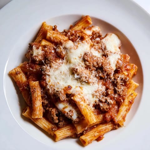 A close-up of a warm, comforting Cheesy Beef & Penne Bake, served with pasta and melted cheese.
