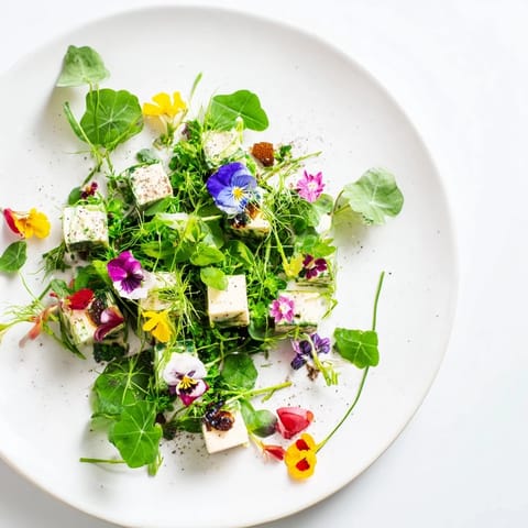 An elegant Secret Garden appetizer, featuring vibrant edible flowers and flavorful cheese treasures.
