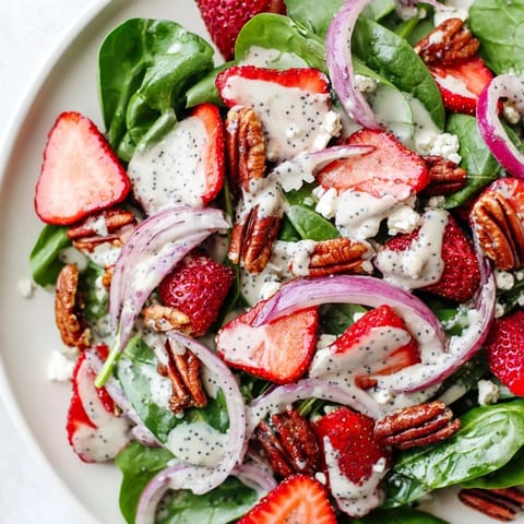 A close-up of a colorful Strawberry Spinach Salad with creamy poppy seed dressing.