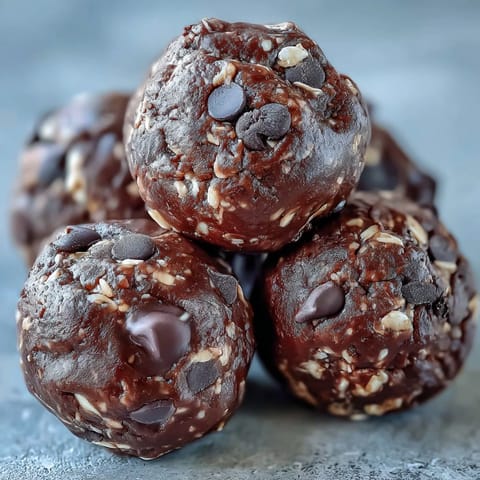 Freshly rolled Vegan Chocolate Peanut Butter Protein Balls with oats and chocolate chips on a parchment-lined tray.