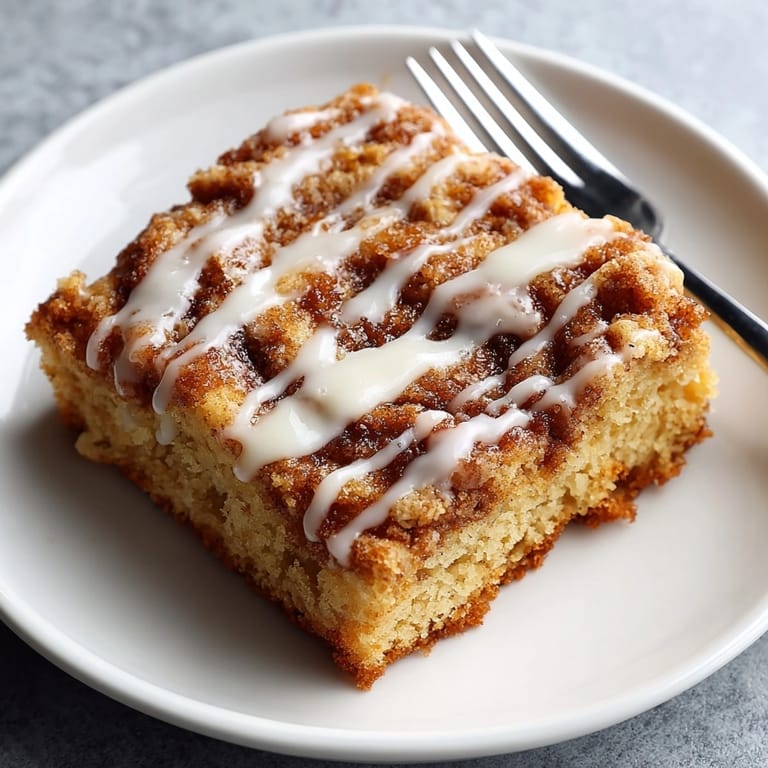 Golden Cinnamon Roll Coffee Cake topped with sweet icing, ready to enjoy with hot coffee.