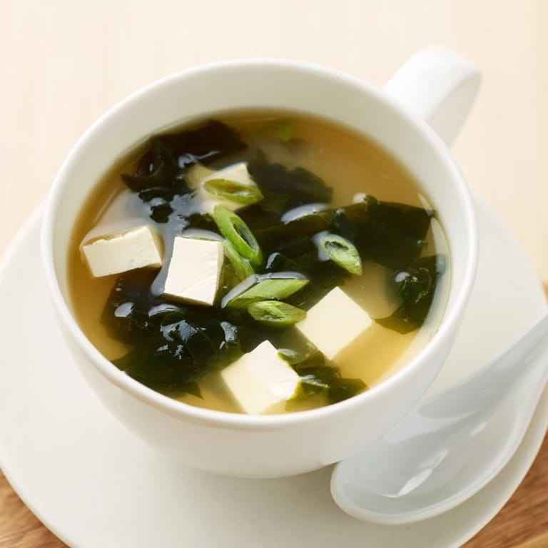 A close-up view shows tender vegetables and soft tofu suspended in the savory Japanese soup, perfect as a light starter or healthy meal.  