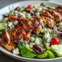 A vibrant Greek salad bowl with grilled chicken, fresh vegetables, and tangy feta cheese, perfect for a healthy summer meal.